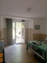 Un dormitorio con una cama, una silla, una puerta que da al exterior y una lámpara en el techo.