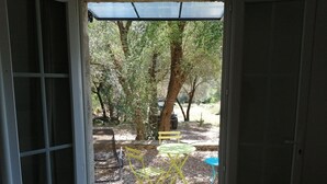Puerta que da a un espacio exterior con un sendero de grava, una silla amarilla y una mesa.