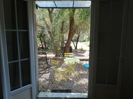 Puerta que da a un espacio exterior con un sendero de grava, una silla amarilla y una mesa.