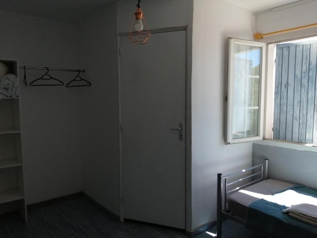 Une pièce comprenant un lit, une armoire, un luminaire suspendu et une fenêtre avec des rideaux.