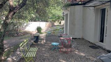 An outdoor seating area with tables and chairs, a dog, and a building with a balcony.