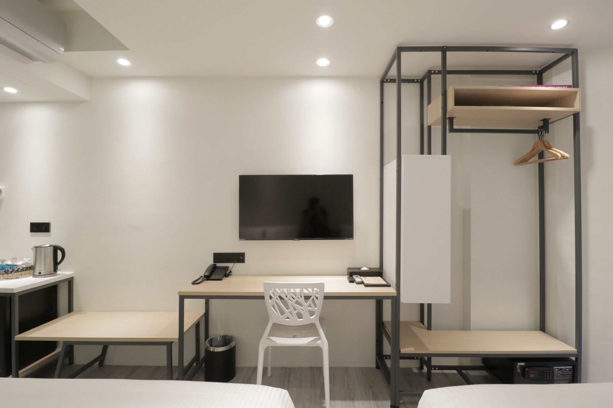 Habitación de hotel con escritorio, silla, televisor, armario y cama.