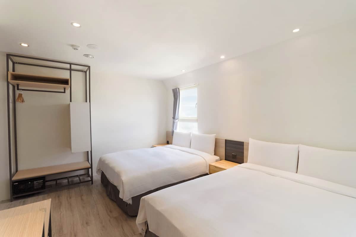 Ein Hotelzimmer mit zwei Betten, einem Schreibtisch und einem Kleiderschrank.