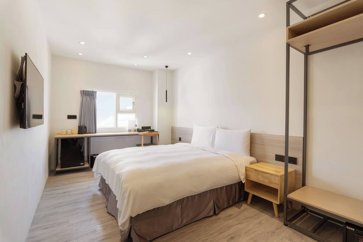 Ein modernes Hotelzimmer mit einem großen Bett, einem Schreibtisch und einem Kleiderschrank.