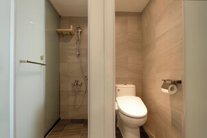 Un baño moderno con ducha, inodoro y un dispensador de papel higiénico en la pared.