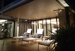 A modern lounge area with two lounge chairs and a bench, wooden flooring, and a ceiling with recessed lighting. - MY LOFT 2 Ratchadapisek36 (Bangkok)