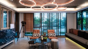 Um interior moderno com área de estar, incluindo poltronas e sofá de couro, mesa de centro de vidro e uma câmera montada em tripé.