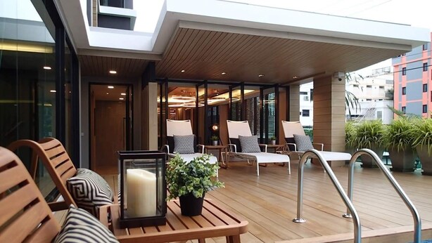 Uma área de estar externa moderna com móveis de madeira, piscina e vista para a cidade.