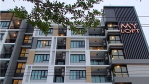 Um hotel moderno de vários andares com um destaque para o letreiro 'MY LOFT', varandas e grandes janelas.
