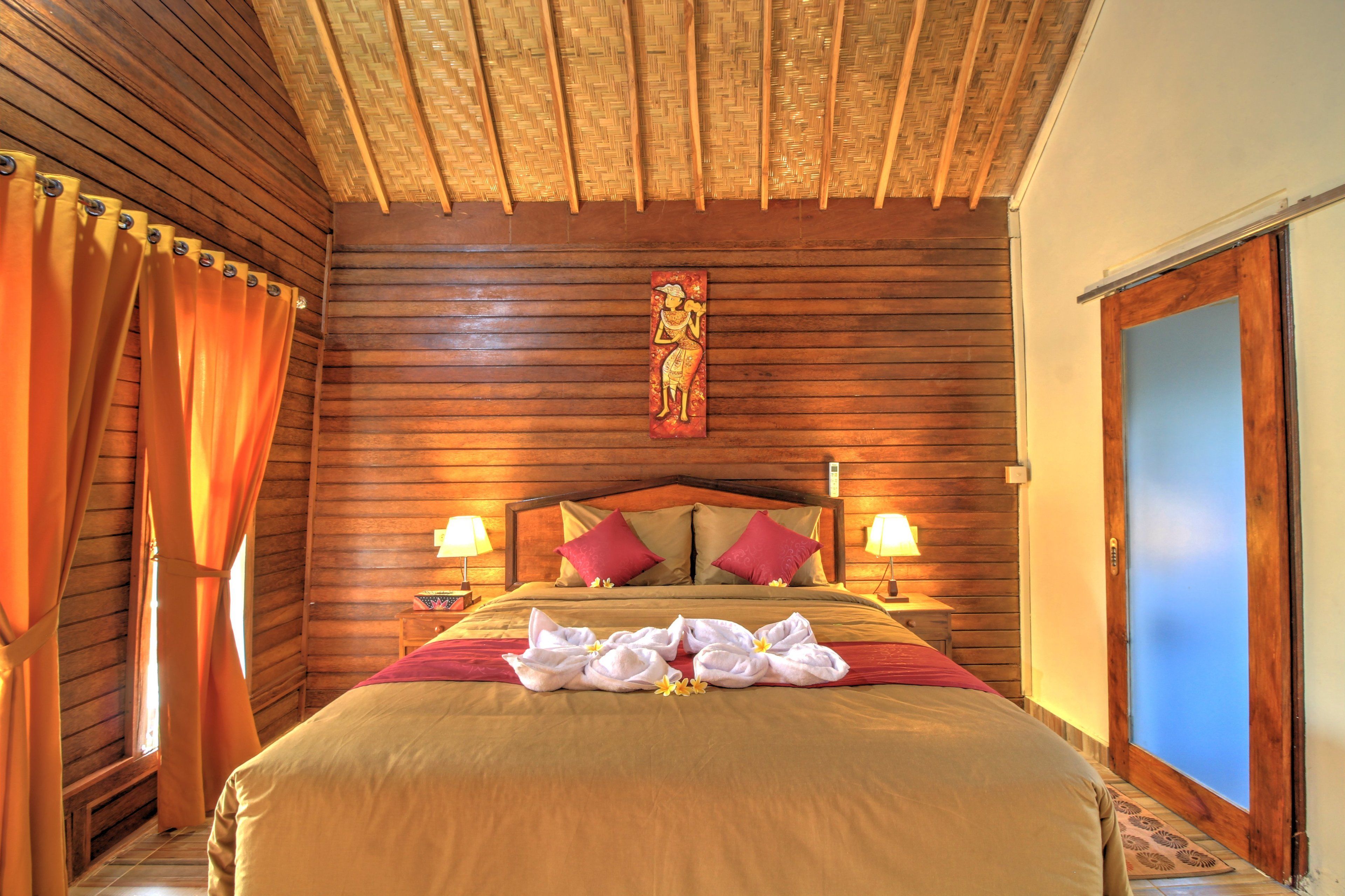 A wooden-paneled room with a bed, two lamps, and a blue door.