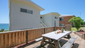 Een terras met een eettafel, een houten omheining en uitzicht op zee.