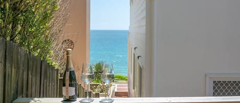 A balcony with a wooden railing overlooking a coastal view.