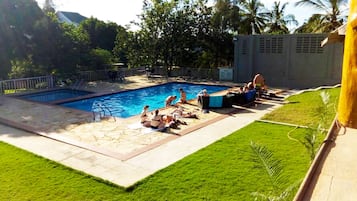 Una piscina al aire libre, sombrillas, sillones reclinables de piscina