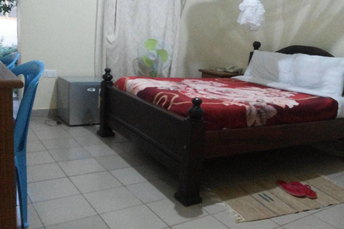 Ein Schlafzimmer mit einem Bett, einem Nachttisch, einem Sessel, einem kleinen Tisch und einer Heizung.