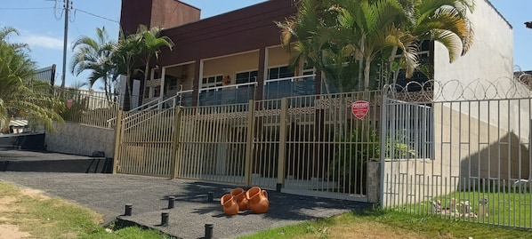A gated property with a metal fence, a paved entrance, and a few potted plants.