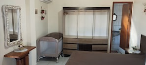 A bedroom with a bed, a bedside table, a wardrobe, and a mirror.