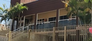 A building with a staircase leading to a balcony, surrounded by palm trees.