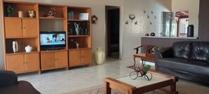 A living room with a television, wooden cabinets, a sofa, and a coffee table.