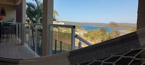 Varanda com vista para um corpo d'água e colinas ao longe.