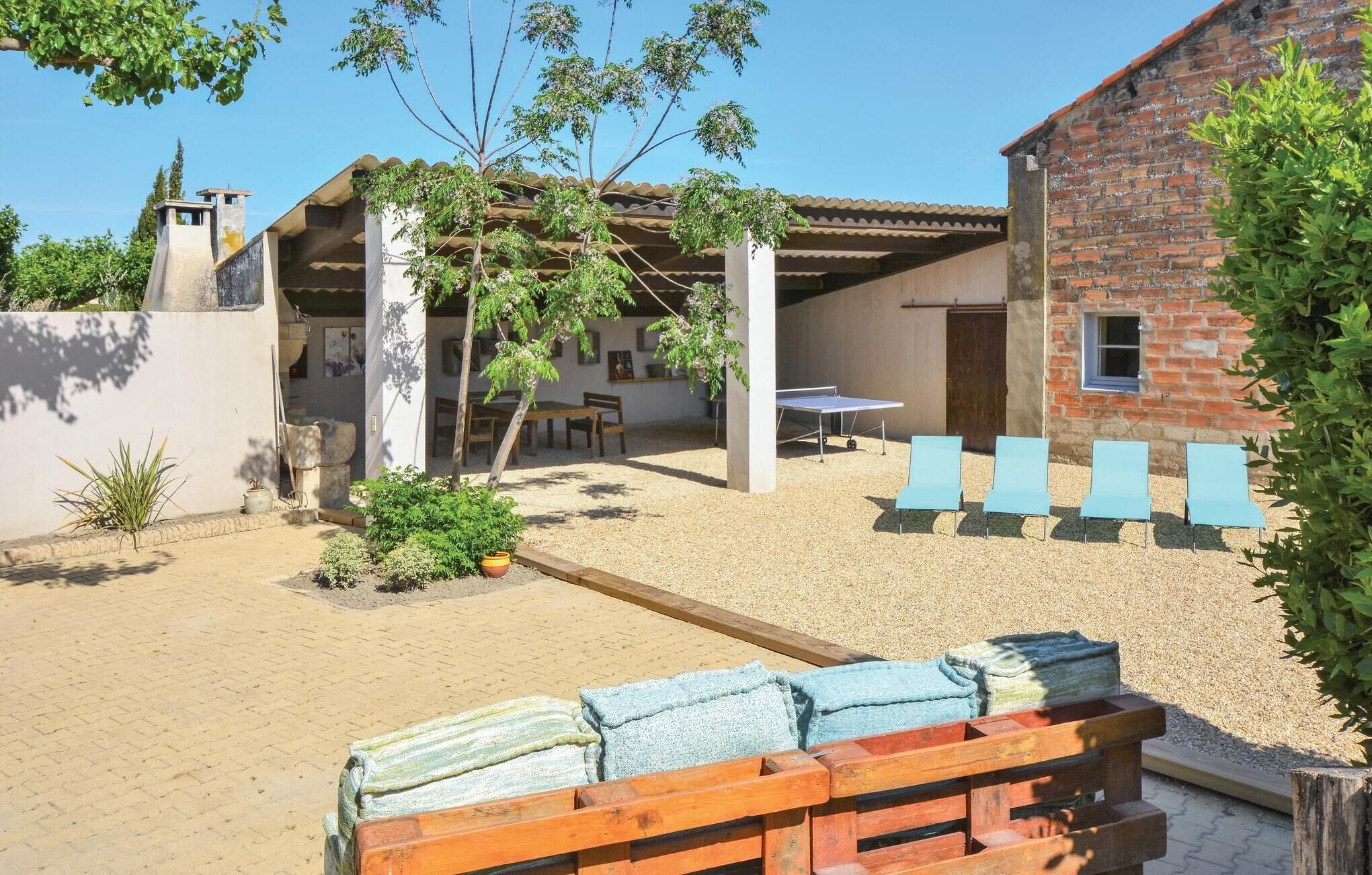 Un patio con mesa de ping pong, mobiliario exterior y un edificio de ladrillo.