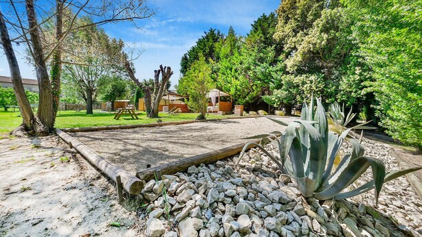 Un jardín con zona de grava, estructuras de madera y diversas plantas.