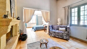 Amplia sala de estar con chimenea, un sofá, una mesa de centro y vista a un dormitorio a través de un vano.