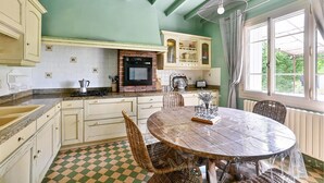 Una cocina con suelo a cuadros, una mesa redonda de madera, sillas de mimbre y una lámpara colgante.