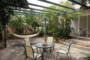 An outdoor patio with a hammock, a round table, and chairs.