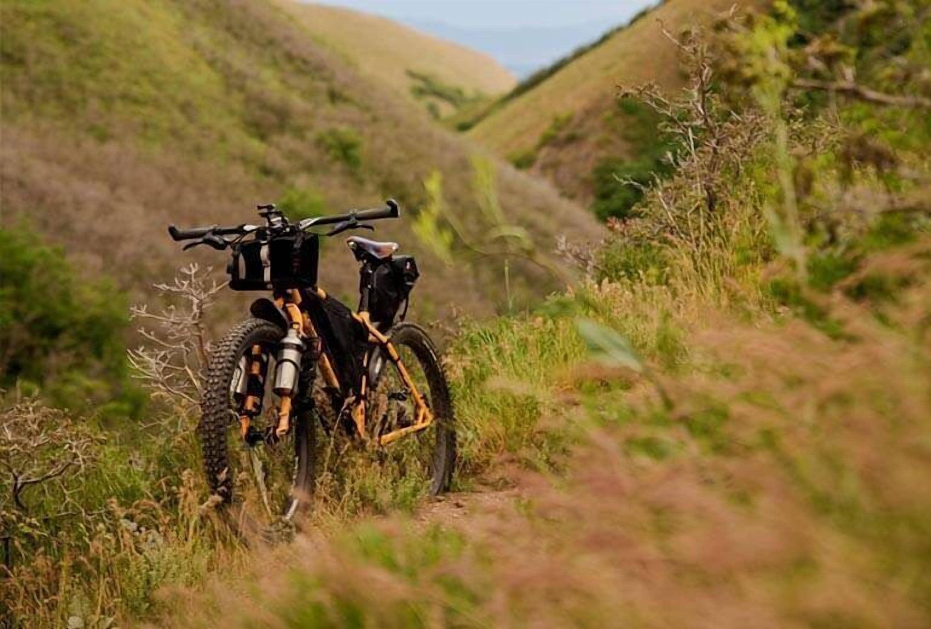 En mountainbike parkeret på en jordvej omgivet af græsbeklædte bakker.