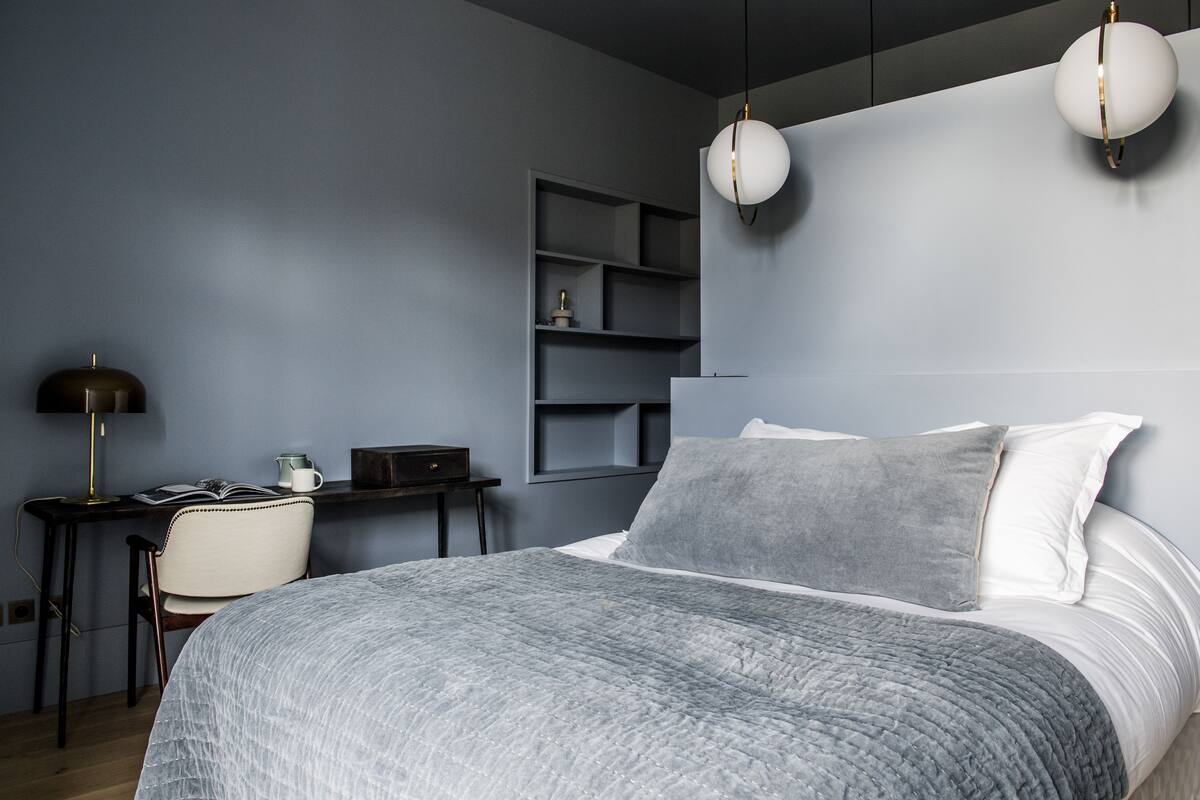Un dormitorio moderno con una cama grande, un escritorio, una silla y estanterías empotradas.