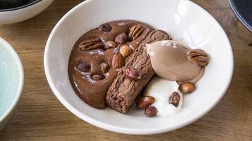 Een nagerechtbord met chocolademousse, koekjes en noten op een houten tafel.