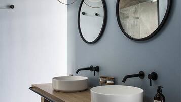 Un baño moderno con dos espejos redondos, un mueble de tocador de madera y un lavabo blanco.
