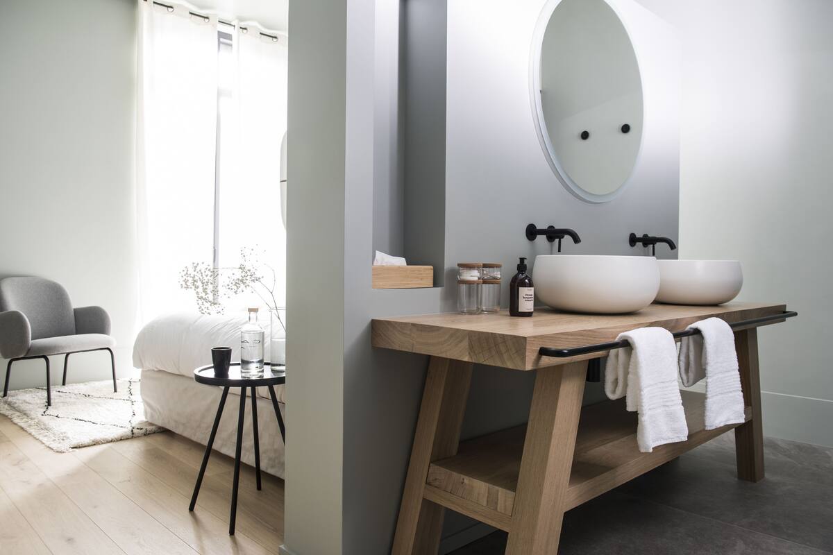 Un baño moderno con tocador de madera, dos lavamanos y un espejo grande.
