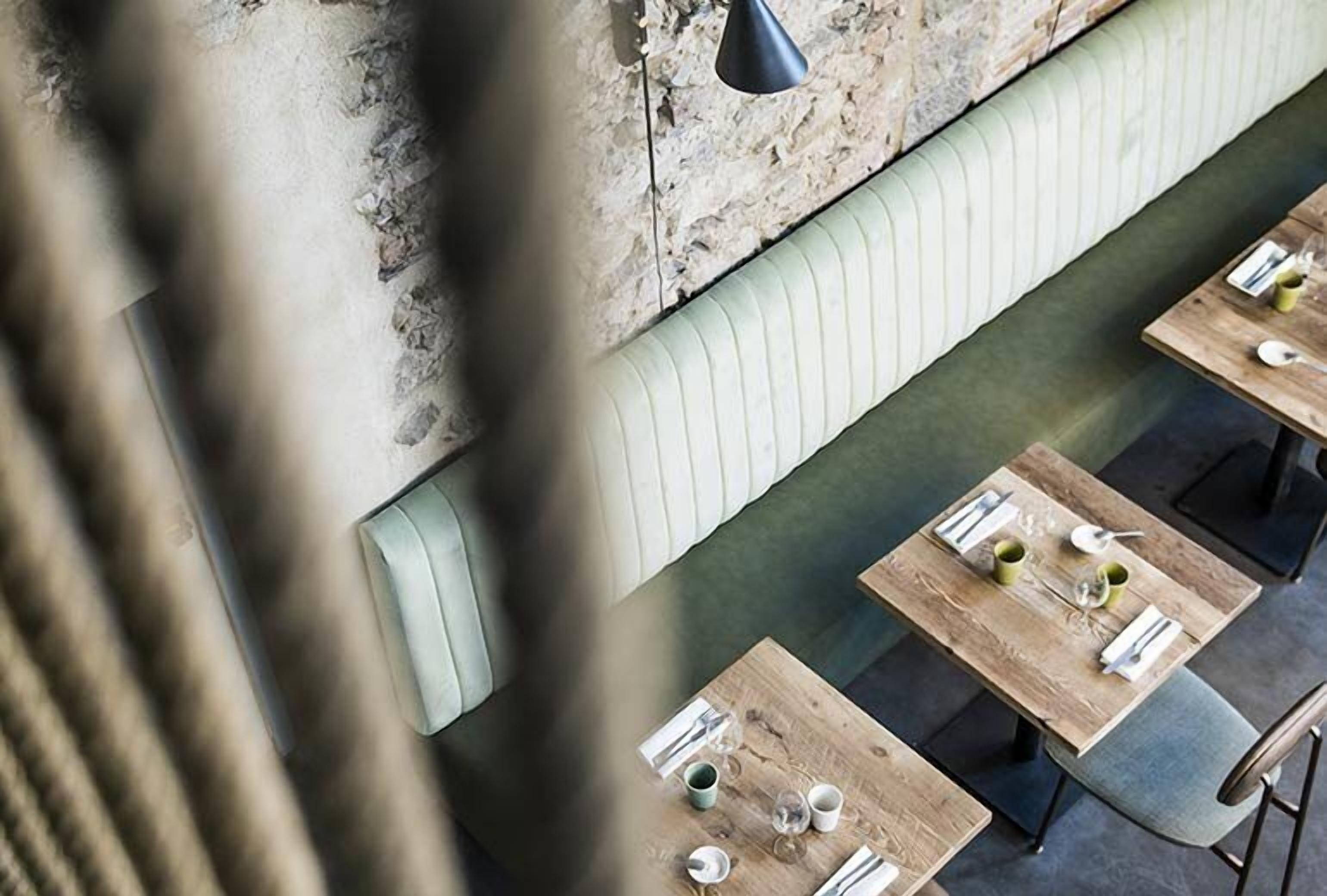 A restaurant with wooden tables and green cushioned benches.