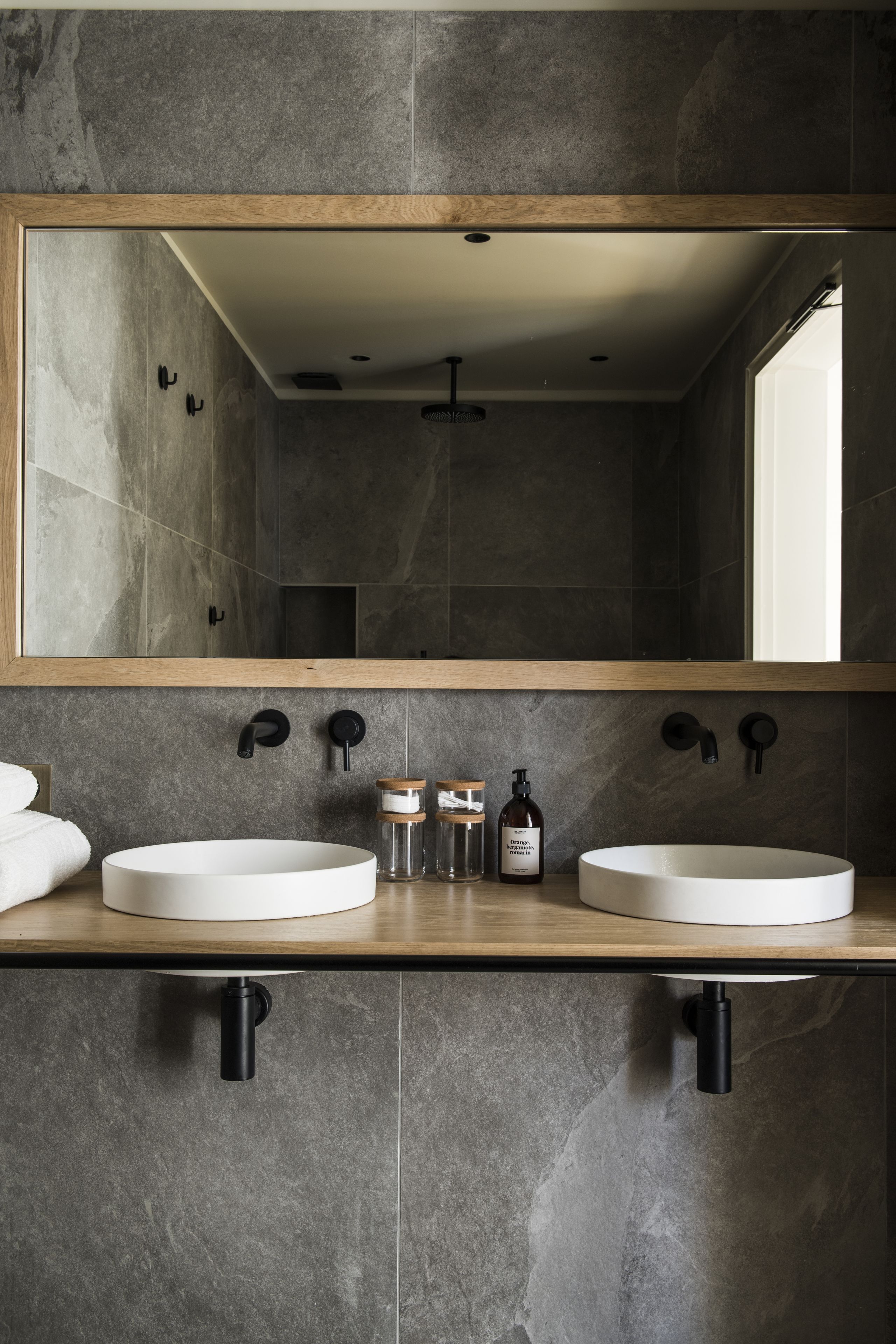 Un baño moderno con dos lavamanos, un espejo grande y una encimera de madera.