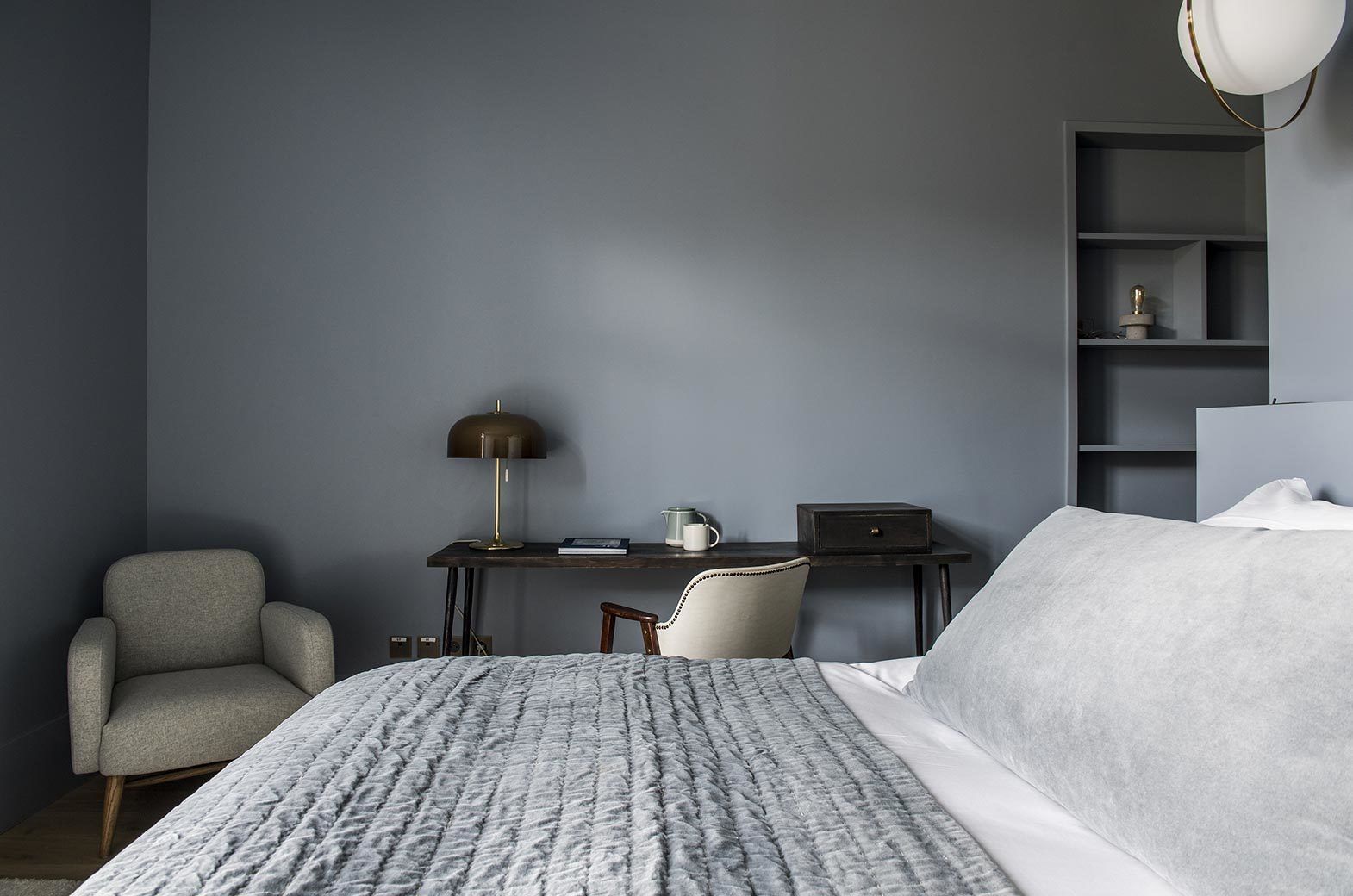 A bedroom with a bed, a desk, a chair, and a bookshelf.