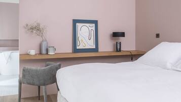 Ein Hotelzimmer mit einem Bett, einem Sessel, einem Regal mit Vase und Bild, einer Lampe und einem Badezimmer im Hintergrund.