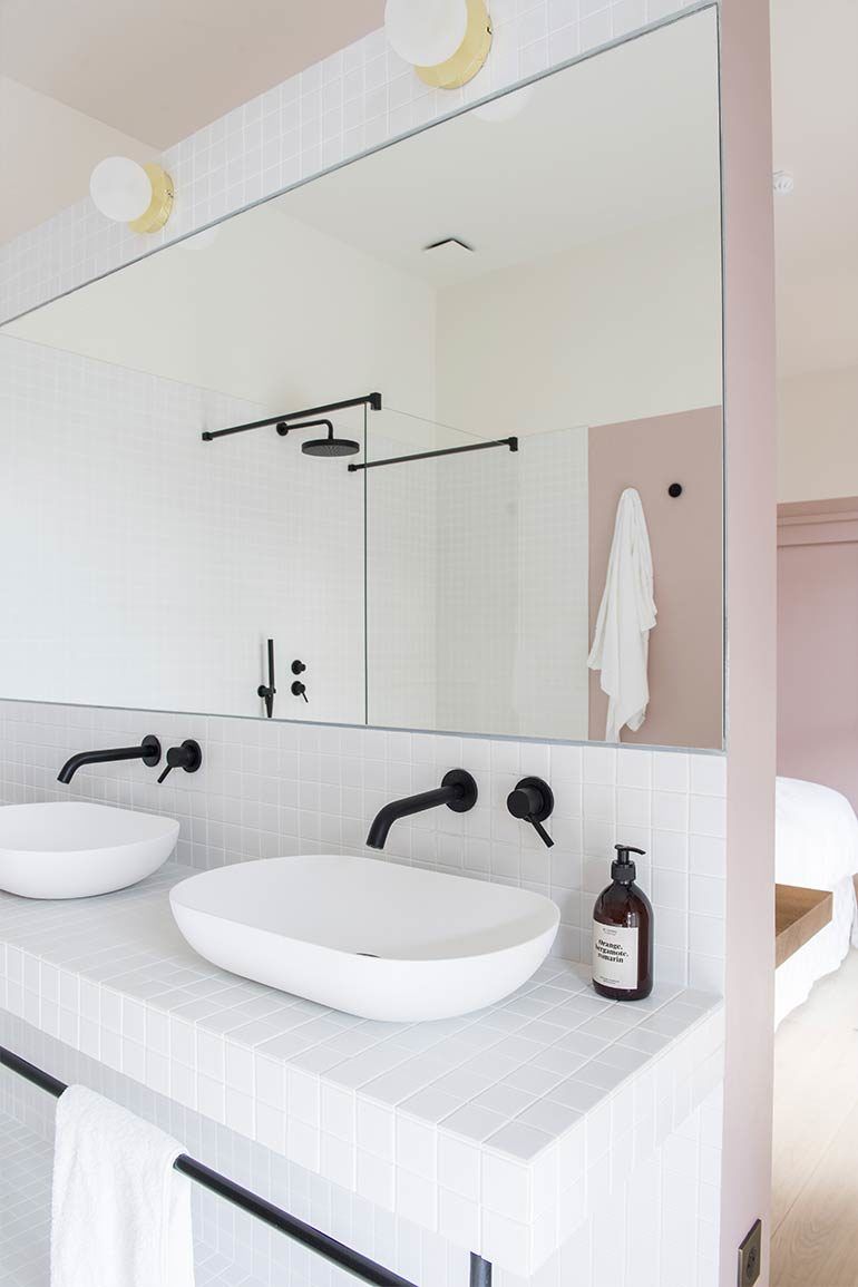 A modern bathroom with two white sinks, a large mirror, and a towel rack.