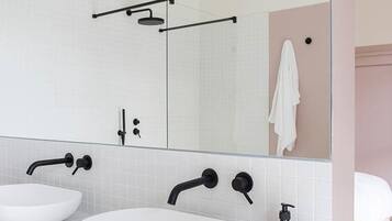A modern bathroom with two white sinks, a large mirror, and a towel rack.