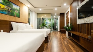 A hotel room with two beds, a TV, a wooden floor, and a painting on the wall. - Nagila Boutique Hotel (Da Nang)
