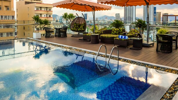A rooftop pool area with a view of the city skyline, outdoor seating, and umbrellas. - Nagila Boutique Hotel (Da Nang)