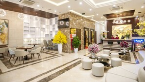 A hotel lobby with a reception desk, seating area, and a large floral arrangement. - Nagila Boutique Hotel (Da Nang)