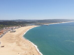 A coastal cityscape with a wide sandy beach, a clear blue sea, and a hilly backdrop. - Nabaía, ground floor new apartment 7-9 pers. with sea view in Salir do Porto (Salir do Porto)