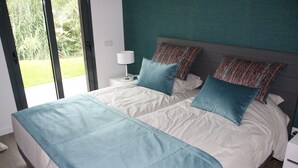 A bedroom with a bed, a nightstand, a lamp, and a view of the outdoors. - Nabaía, ground floor new apartment 7-9 pers. with sea view in Salir do Porto (Salir do Porto)