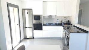 A modern kitchen with white cabinetry, a stainless steel refrigerator, a built-in oven, a microwave, a sink, and a dishwasher. - Nabaía, ground floor new apartment 7-9 pers. with sea view in Salir do Porto (Salir do Porto)
