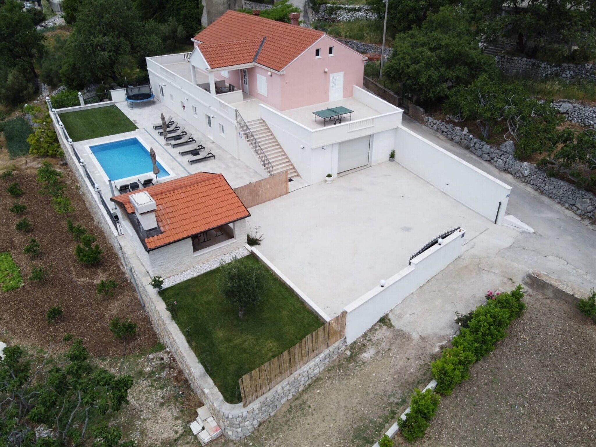 A two-story house with a swimming pool, a covered patio, and a large open driveway.