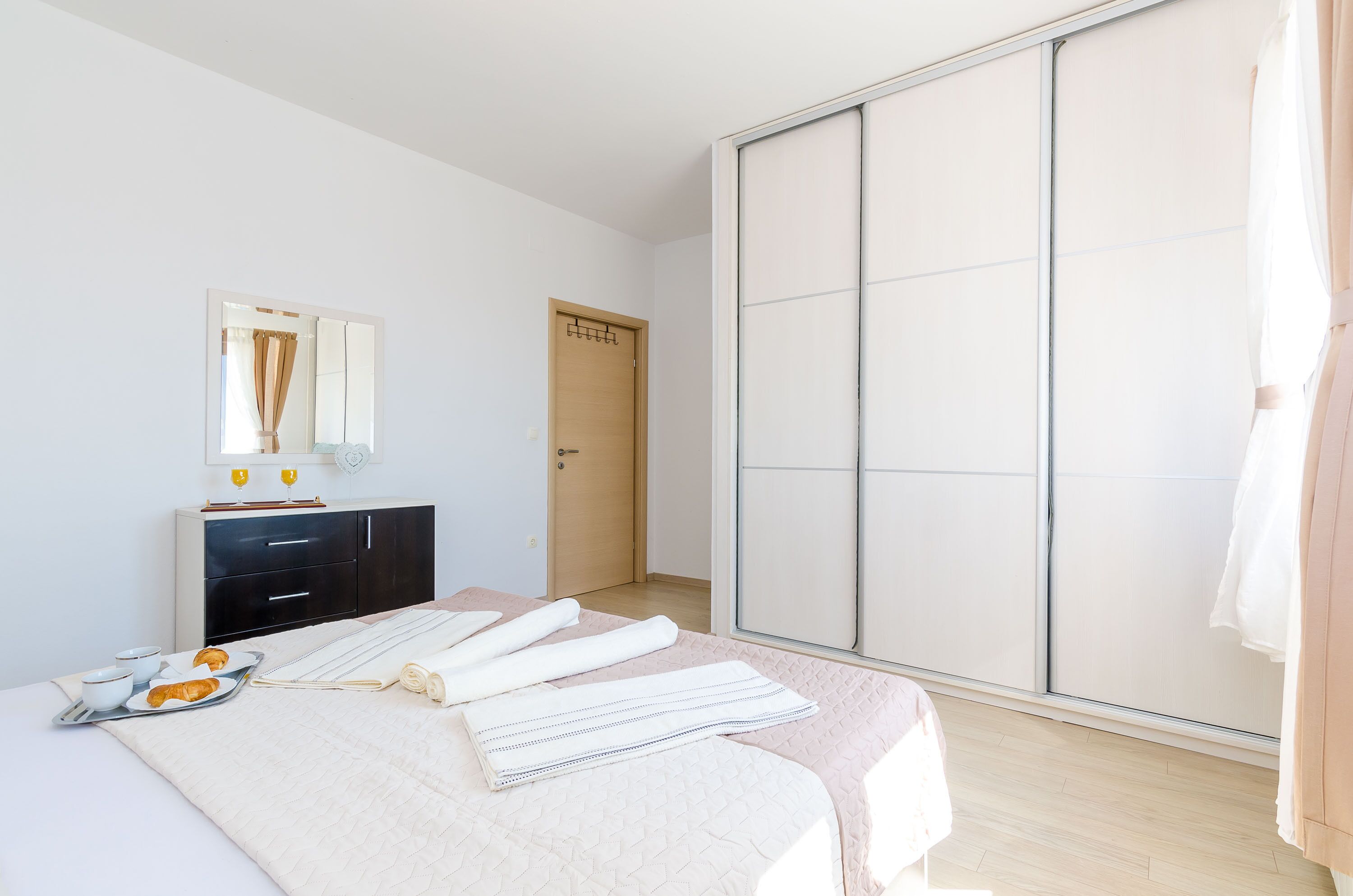 Un dormitorio con cama, armario, espejo y puerta.