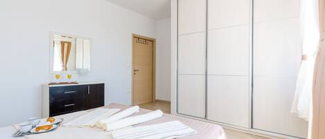Un dormitorio con cama, armario, espejo y puerta.