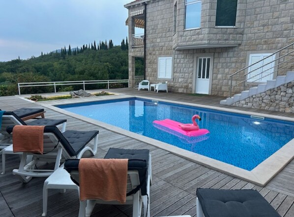Une piscine avec des chaises longues et un flotteur en forme de flamant rose.