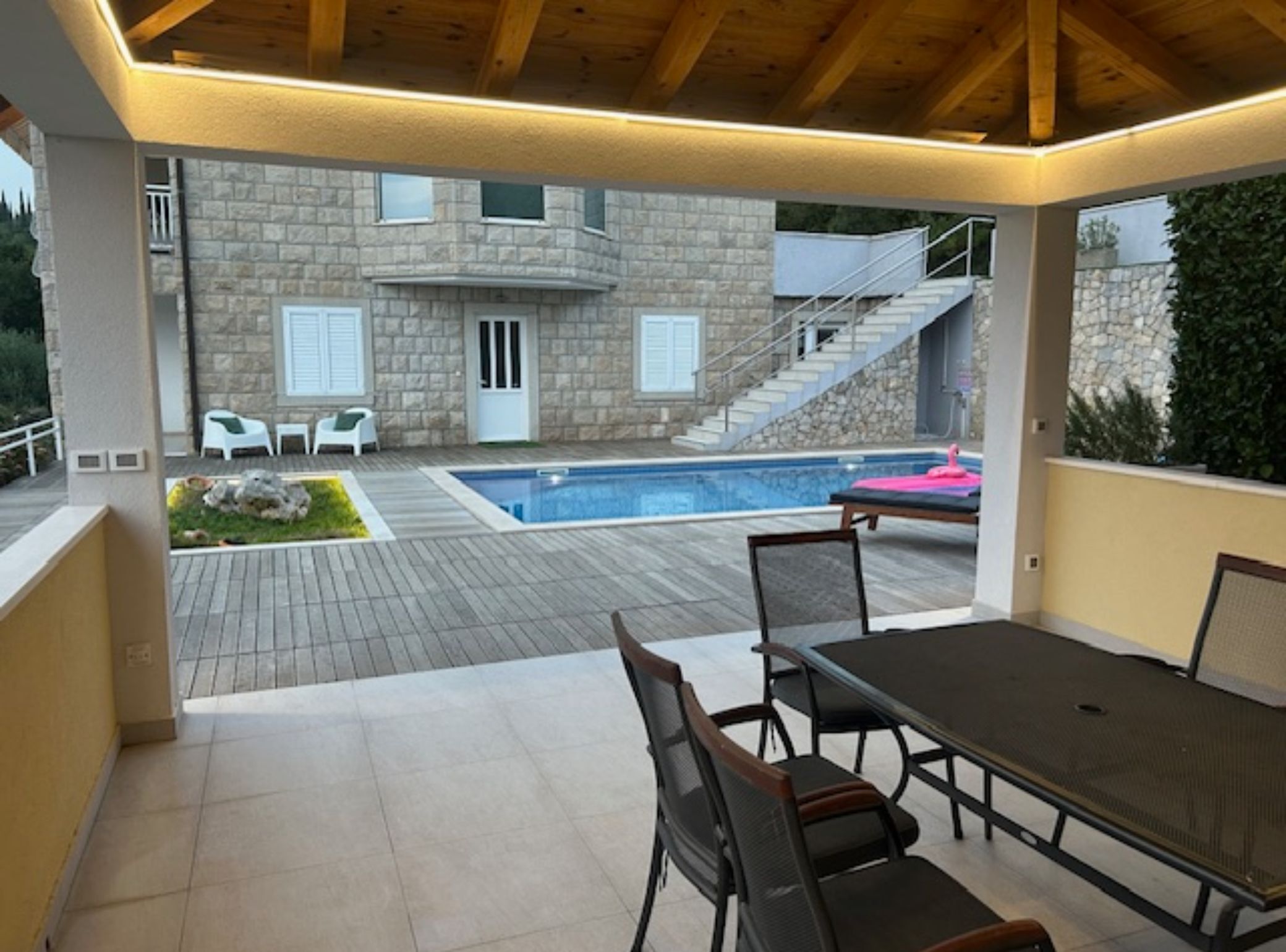 Un espace extérieur aménagé avec une terrasse, une piscine, un bâtiment en pierre et des sièges.